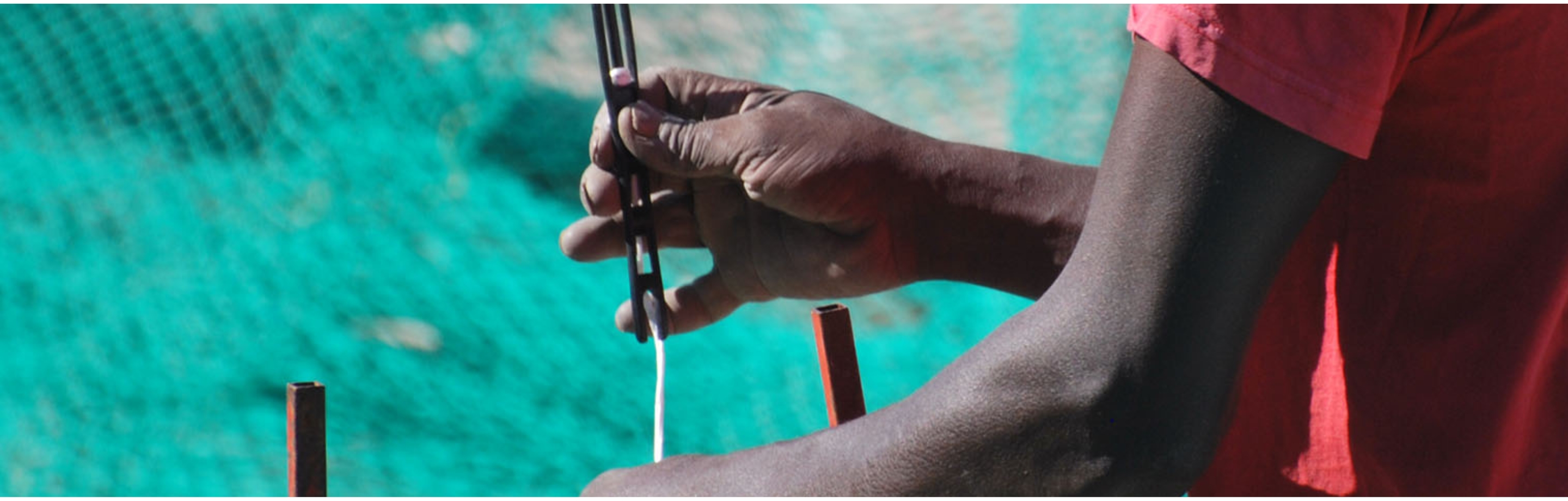 Imagen de pescador negro cosiendo red de pesca