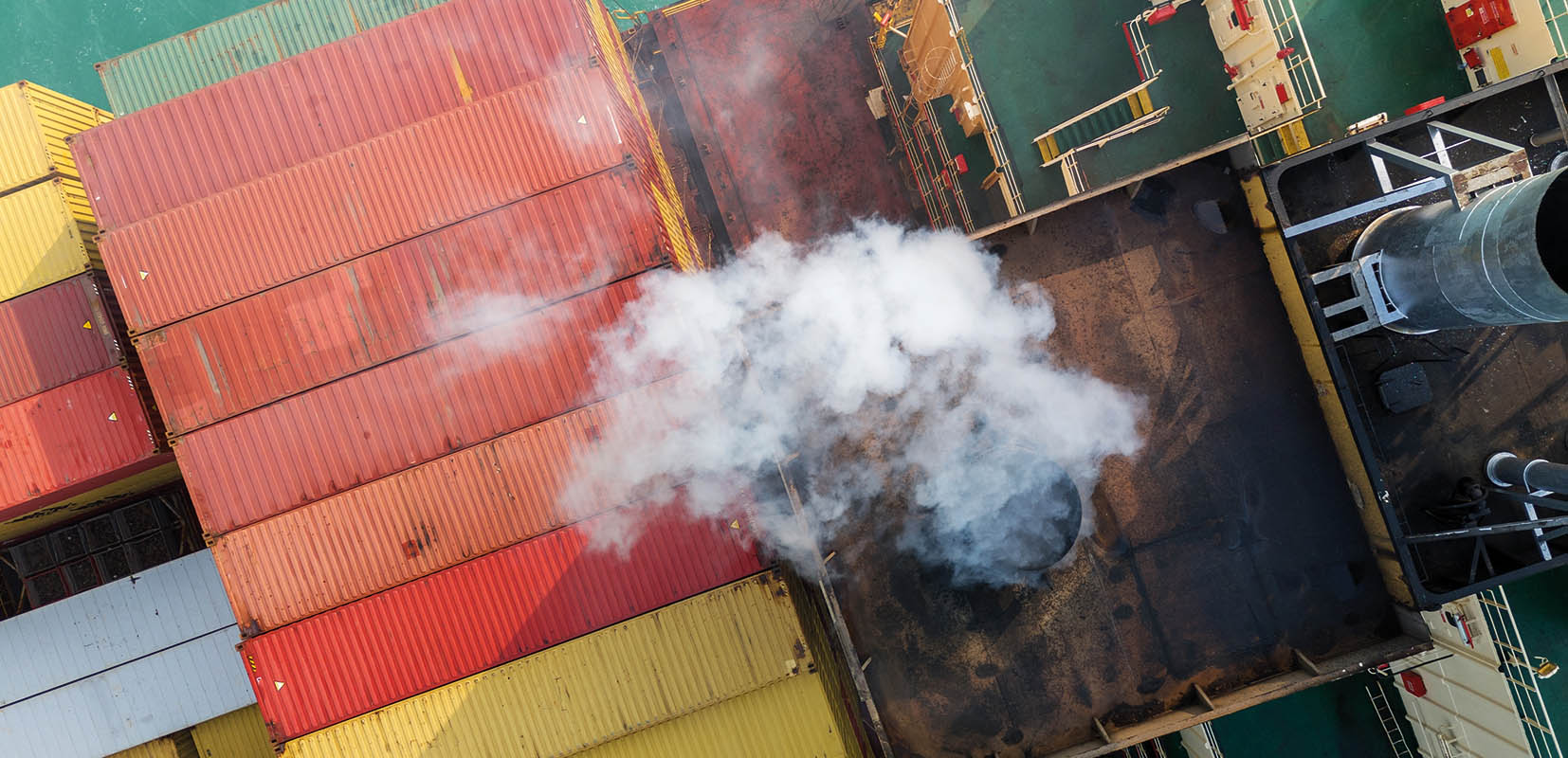 Contenedores sobre barco carguero rodeados del humo de la combustión.