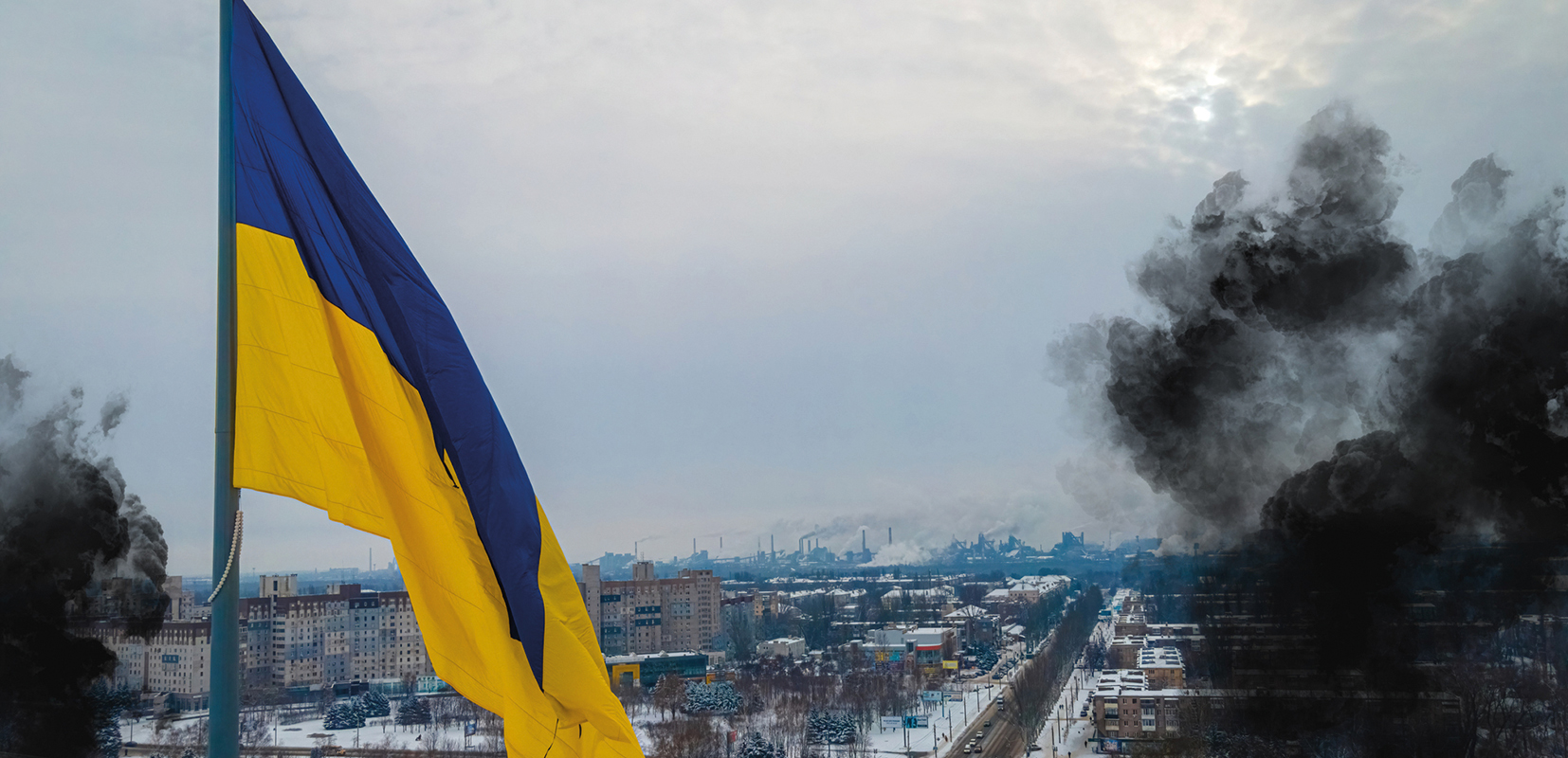 Imagen de la bandera de Ucrania en un paisaje nevado con humo por los bombardeos
