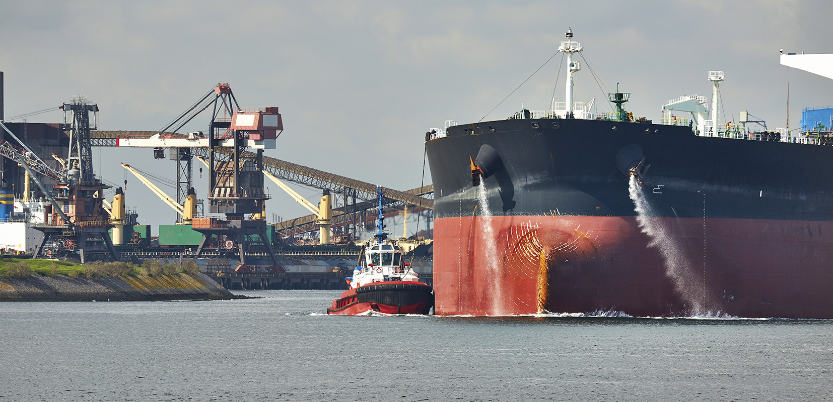 Gran buque petróleo crudo bombeando agua de lastre cuando llega al puerto de Rotterdam