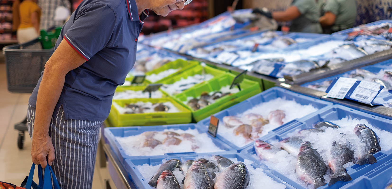 Un vendedor de pescado en un mercado de mariscos sacando un filete de pescado congelado del refrigerador