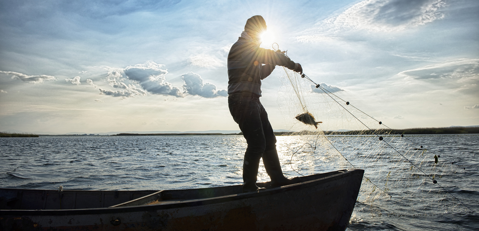 Pescador lanzando una red desde su barca