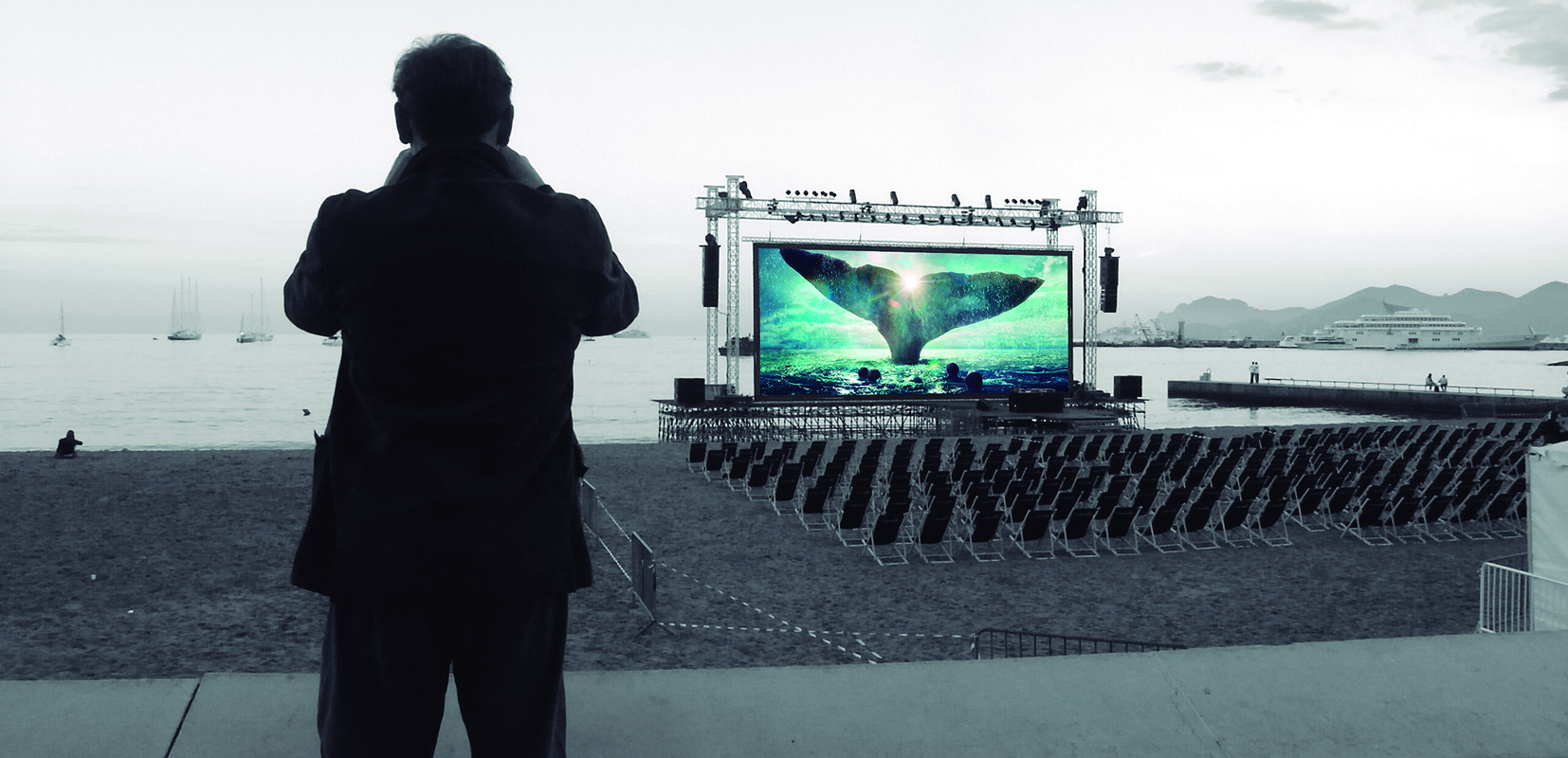 hombre mirando pantalla de cine en la playa