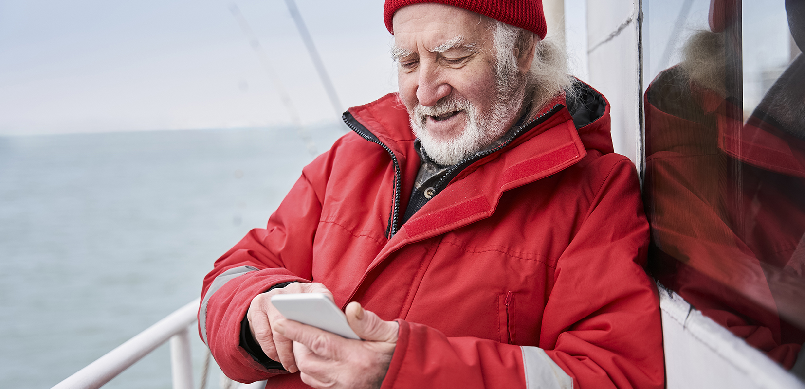marinero consultando su móvil desde la cubierta de un barco 