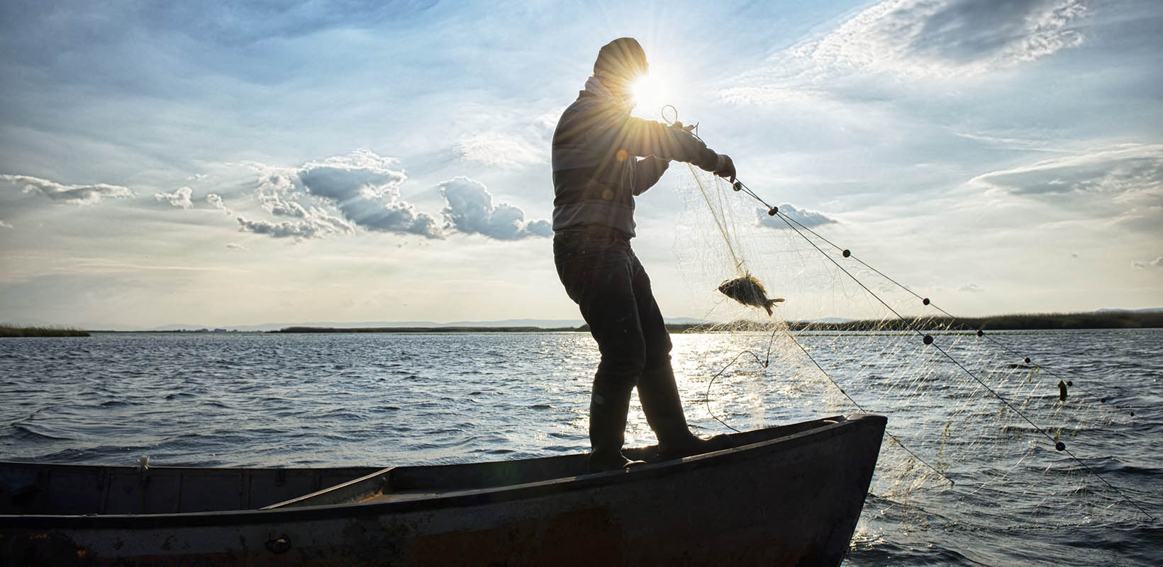 Un pescador lanza una red desde su barca