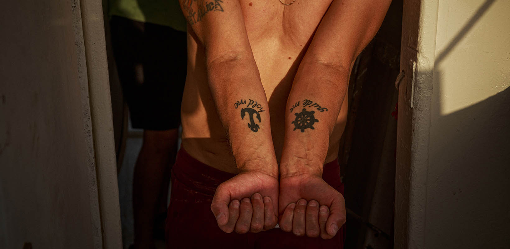 Ancla y timón tatuados en los brazos de un marinero