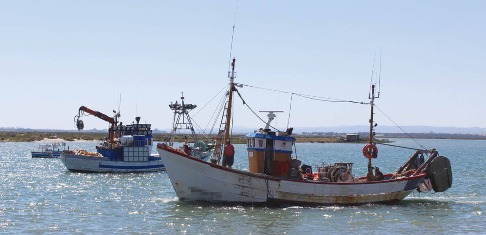Imagen de cuatro pescadores en un barco en el puerto de L'Atmella de Mar (Tarragona)