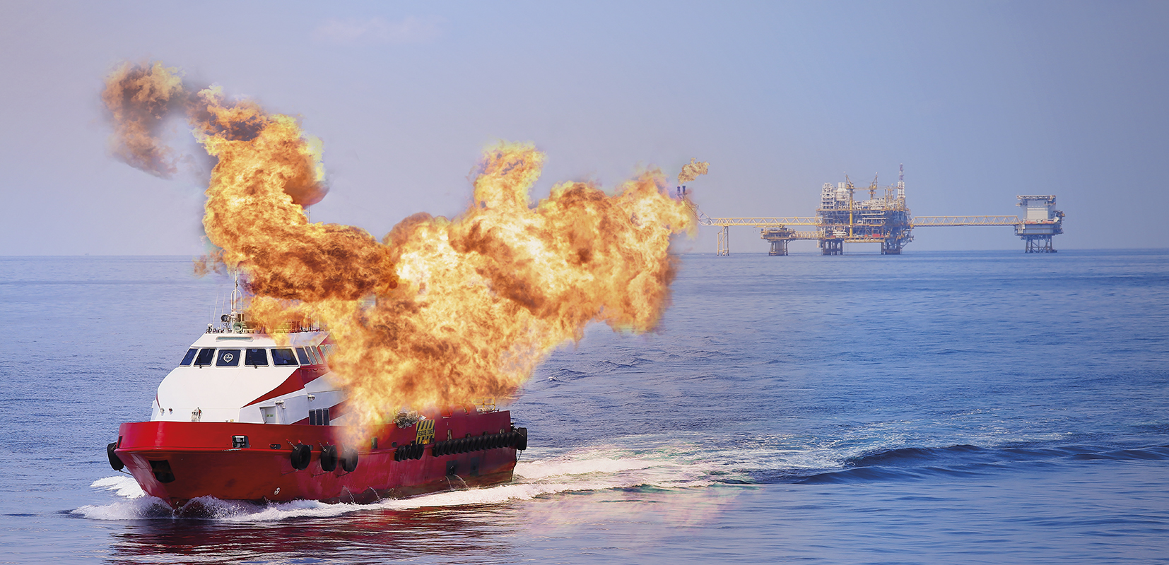 barco ardiendo con estación petrolera al fondo 