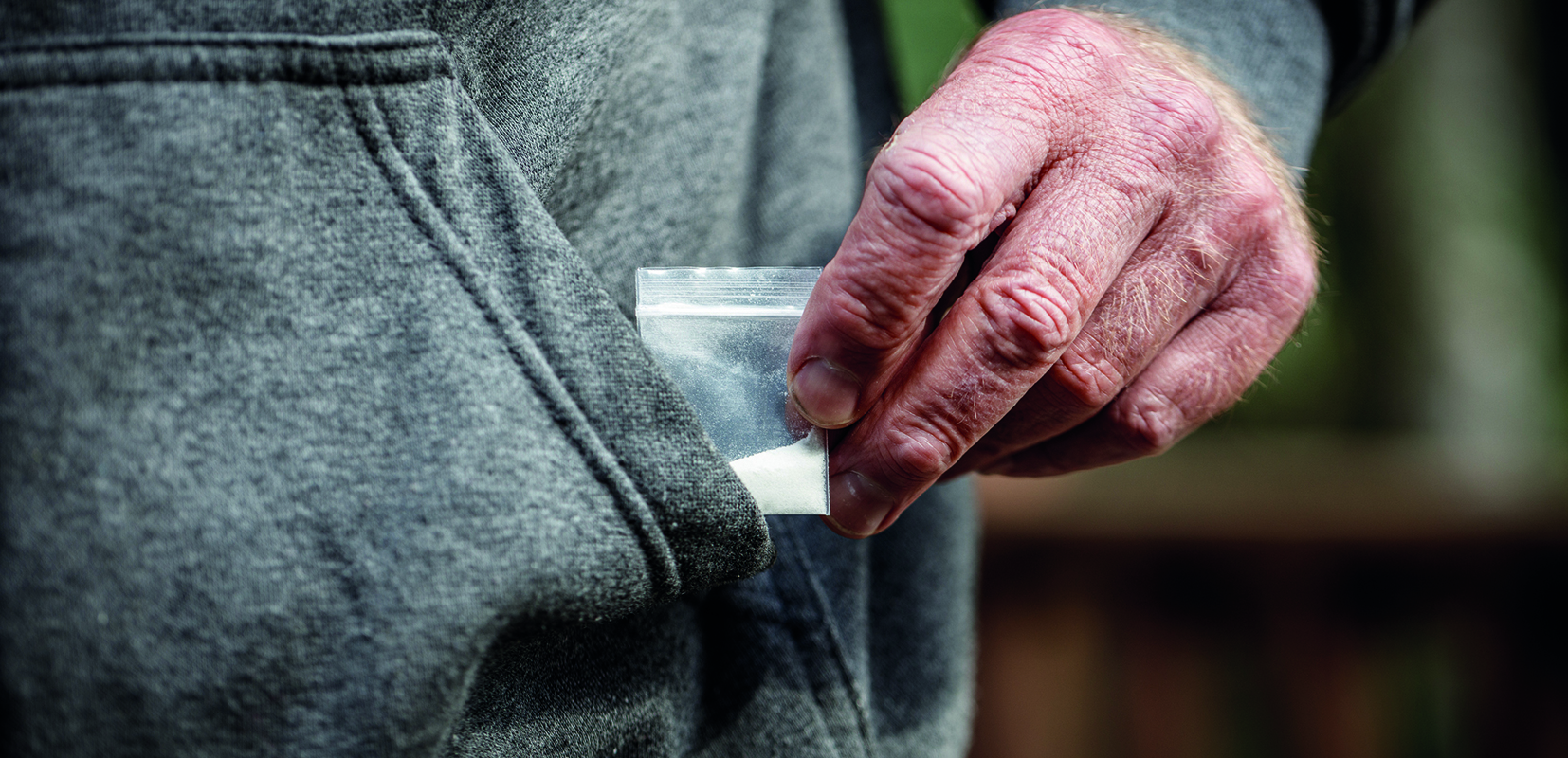 Persona mayor con papelina de droga escondida en el bolsillo