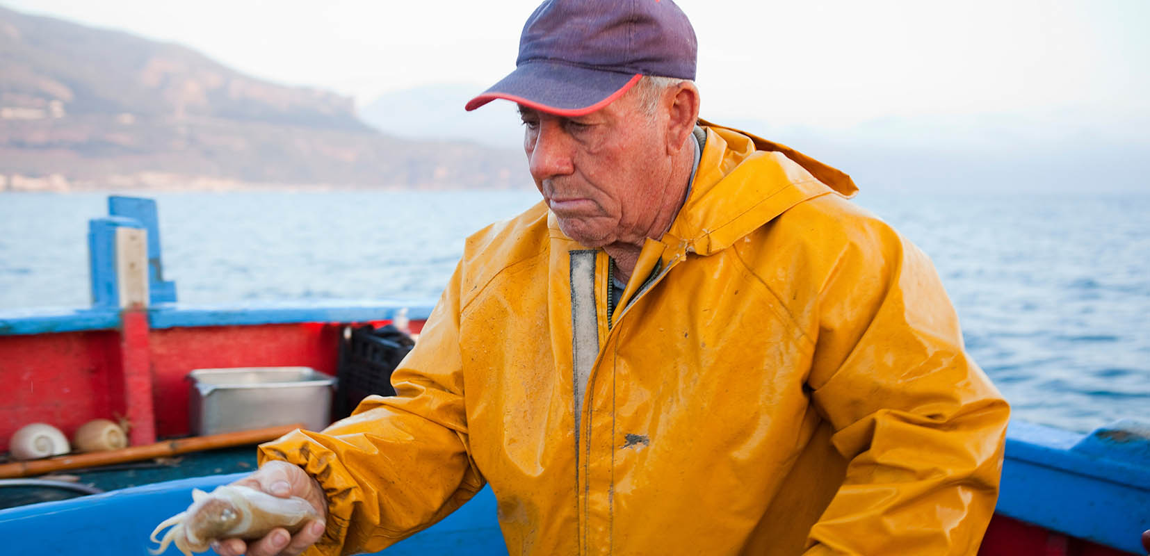 Listado vertical: pescador quemado por el sol con un calamar en la mano
